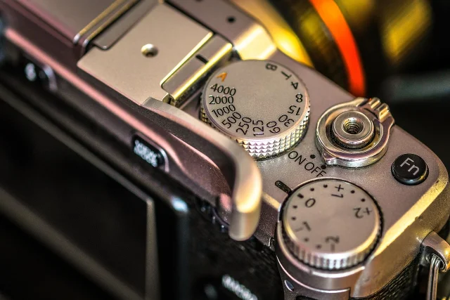 Fujifilm camera top plate close-up showing shutter speed dial and controls, silver with black accents