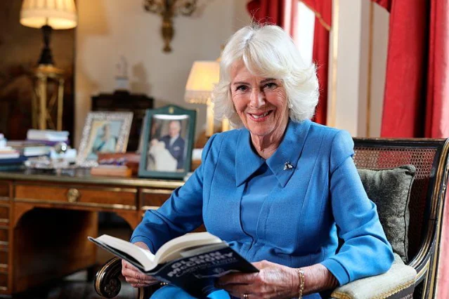 Queen Camilla seated in a reading chair holding an open book