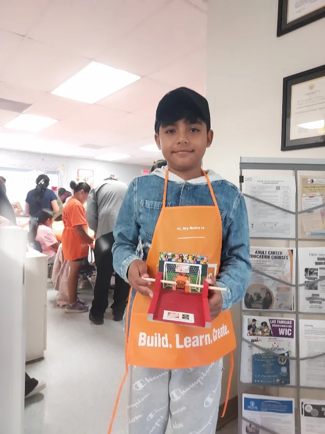 A child at the CSUF Center for Healthy Neighborhoods holds the tabletop game he made.