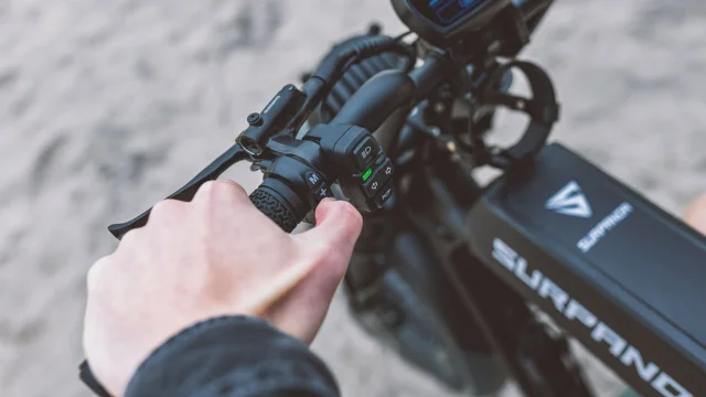 Hand pressing assist level buttons on an eBike handlebar control unit