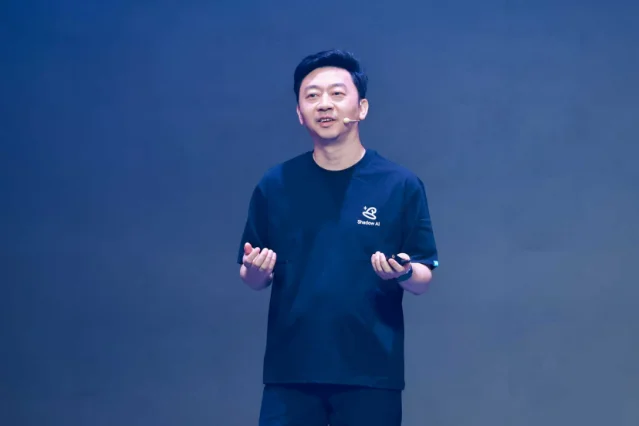 出门问问创始人李志飞在演讲台上，身穿印有 Shadow AI 字样的深色短袖