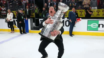 Rod Brind'Amour in a black suit, embracing the Stanley Cup in a bear hug on the ice at T-Mobile Arena