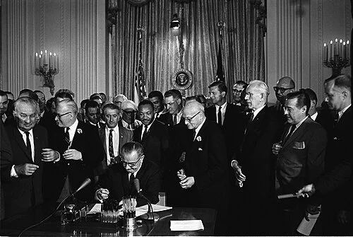 President Lyndon B. Johnson signs the Civil Rights Act on July 2, 1964, surrounded by Congressional leaders and civil rights figures