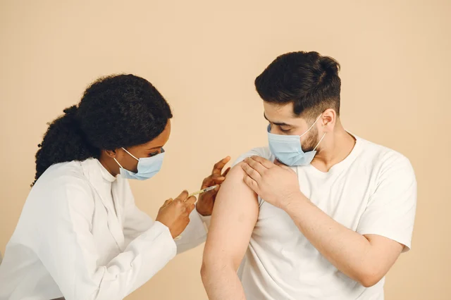 Healthcare worker administering a vaccine to a patient in a clinical setting