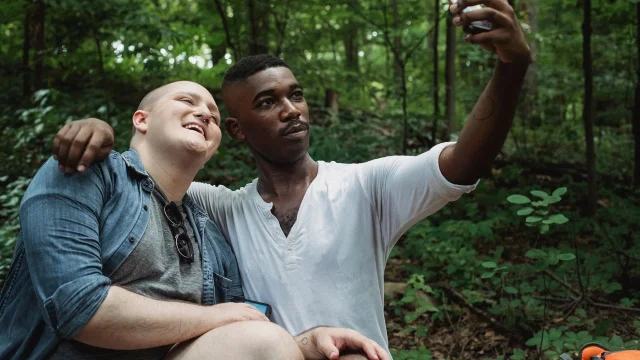 Two men taking an outdoor selfie together, representing the real-world connections Grindr's Edge tier is designed to optimize