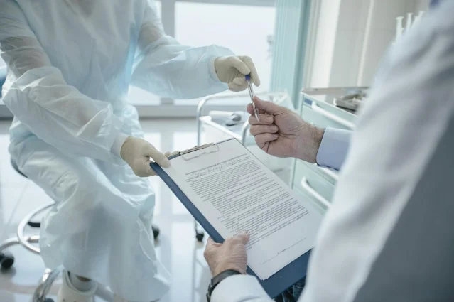 A doctor handing a document to a patient for signature in a clinical setting