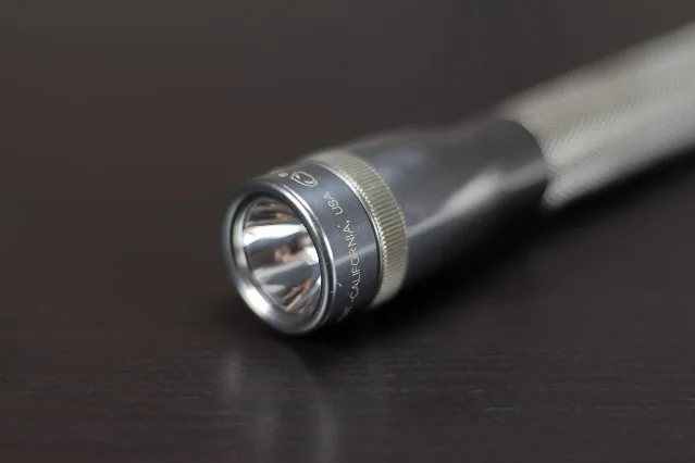 A metal torch lying on a dark surface