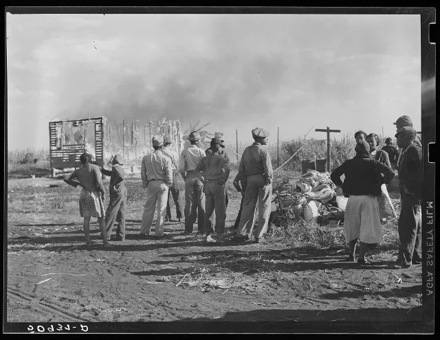 Marion Post Wolcott's 1939 photograph of agricultural laborers watching a house burn near Lake Harbor, Florida.
