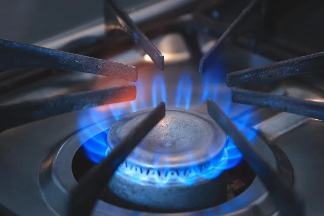 A blue gas flame surrounded by a metal burner cap and grate supports