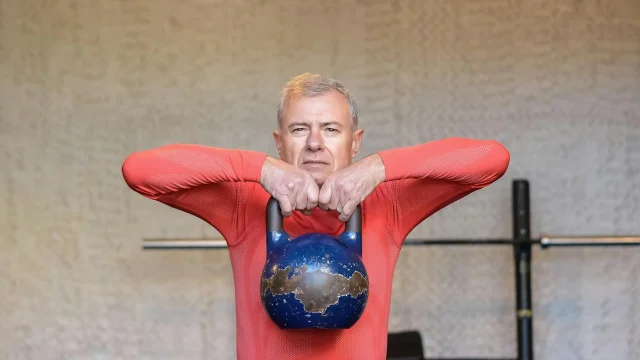 Elderly man lifting a kettlebell, representing strength training for frailty reversal in older adults