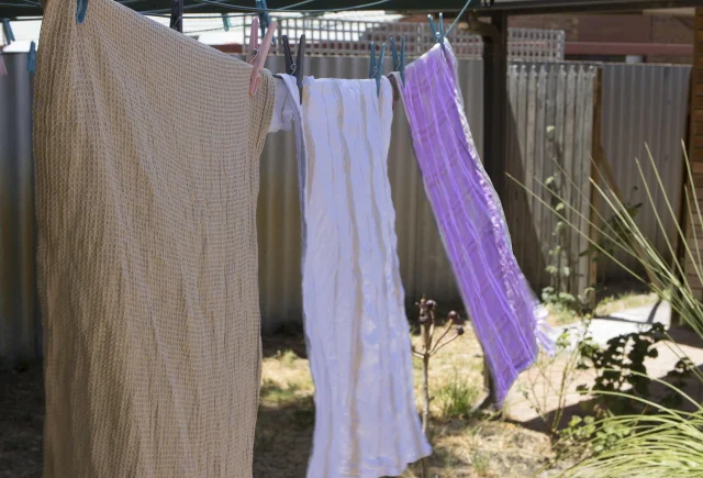 Waffle-weave and cotton dishcloths hanging spread out on a line to air-dry in the breeze
