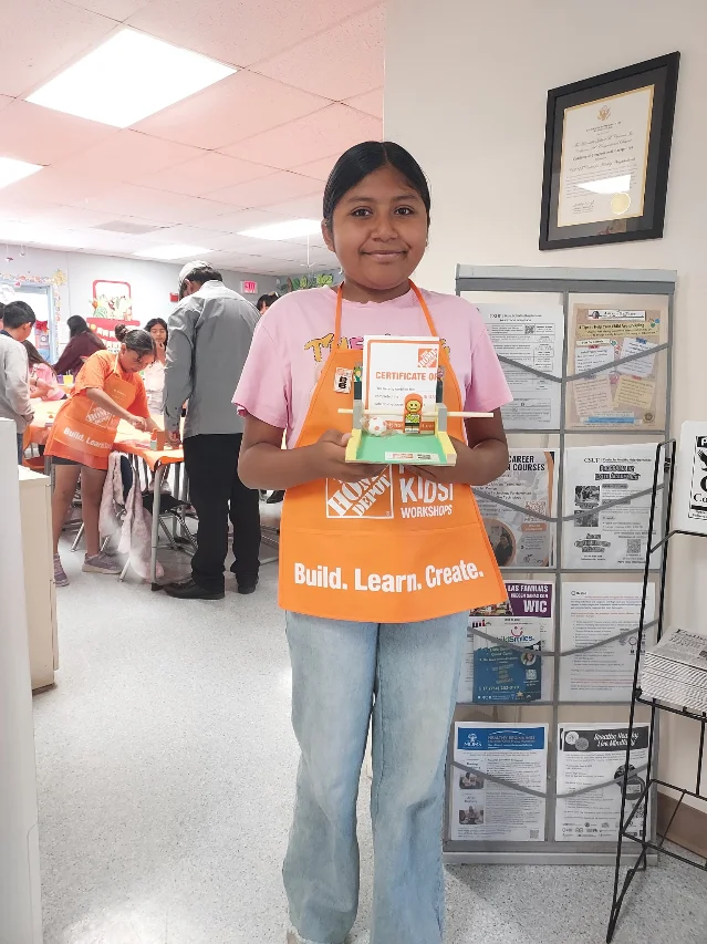 A girl holds up her finished tabletop game at the Center for Healthy Neighborhoods.
