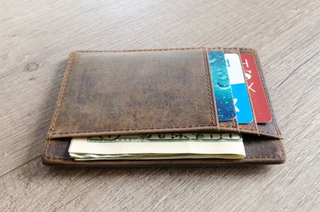 Brown leather wallet with credit cards on a wooden surface
