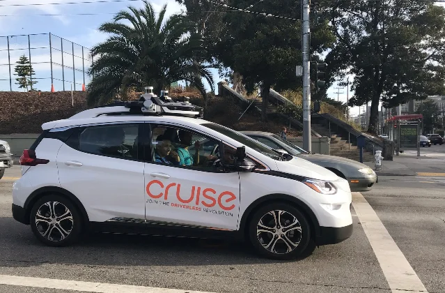 旧金山街头的一辆 Cruise 自动驾驶测试车,车顶装有传感器阵列,驾驶位上有测试人员