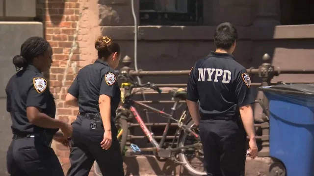 三名 NYPD 警员在布朗克斯街道步巡,背景为砖墙与停靠的自行车