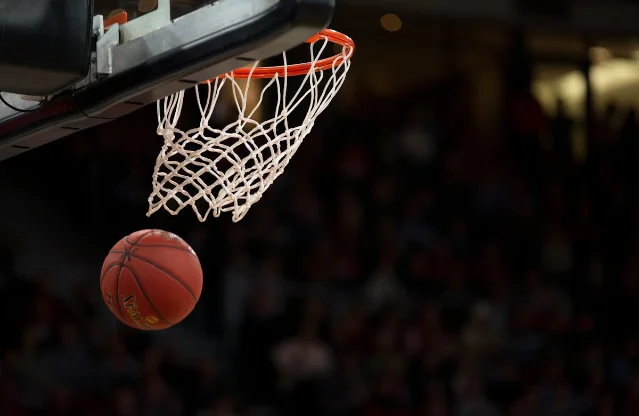 Basketball players competing for a rebound under the basket during a college game