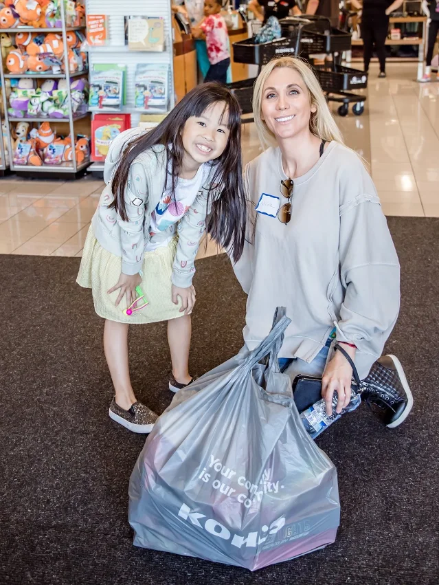 A child and volunteer pose with shopping bags during a Boys & Girls Clubs back-to-school shopping event.