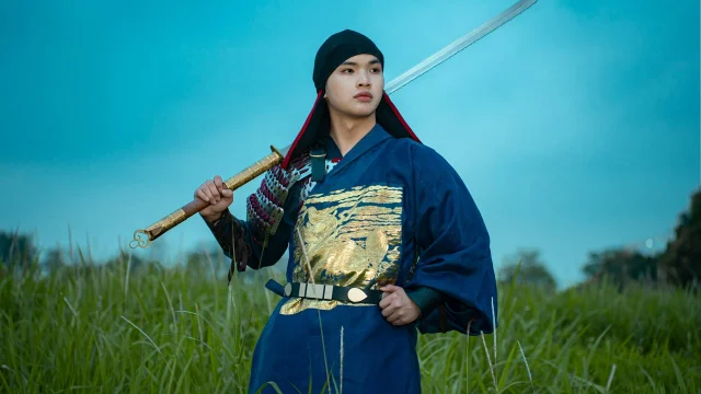 Samurai warrior holding sword in a grassy field at twilight