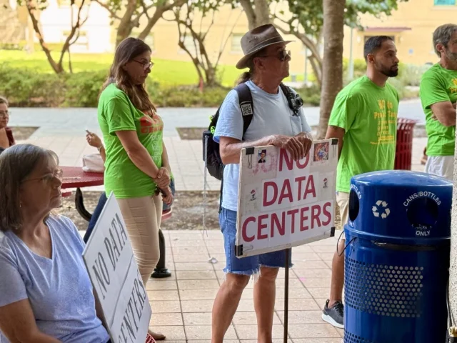 Residents hold signs during a Palm Beach County Commission meeting about Project Tango