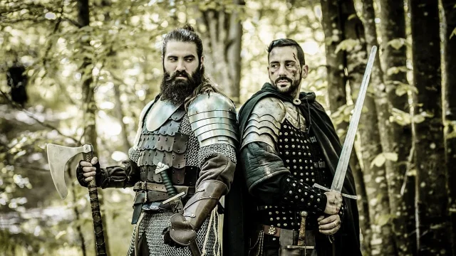 Two medieval warriors in armour, standing back to back in forest