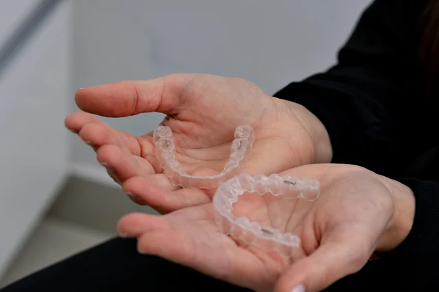 Hands holding a clear dental aligner in a modern dental clinic