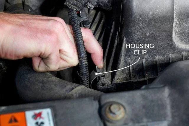 Hands opening the engine air filter housing