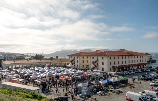 Wide-angle view of Fort Mason's historic waterfront campus with the Bay Bridge in the background at dusk