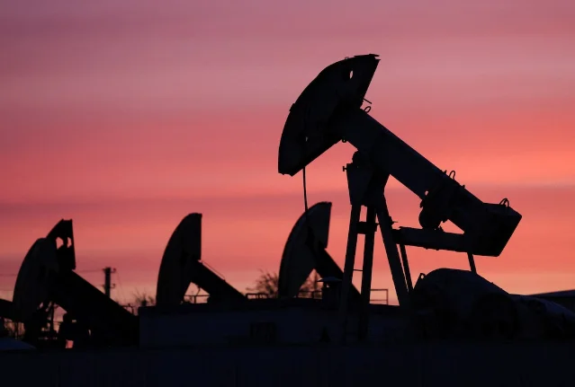 Oil pumpjacks silhouetted against a red evening sky