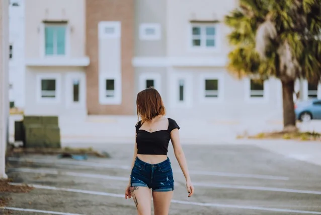 Woman in black fitted square-neck crop top and denim shorts, street setting