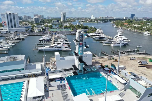 Fort Lauderdale Aquatic Center venue with high diving tower alongside luxury yachts
