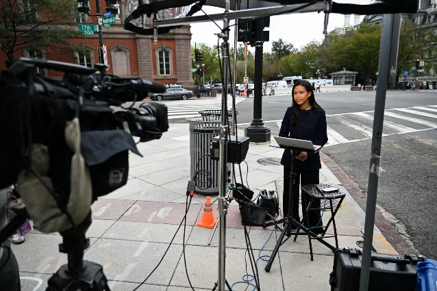 CNN 记者 Betsy Klein 站在白宫外的人行道上,用支架搭起的简易机位做连线