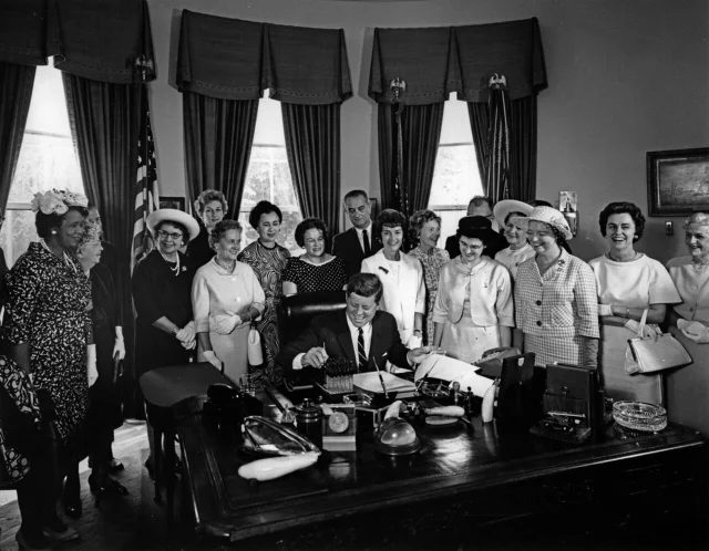 President John F. Kennedy signing the Equal Pay Act, surrounded by AAUW members