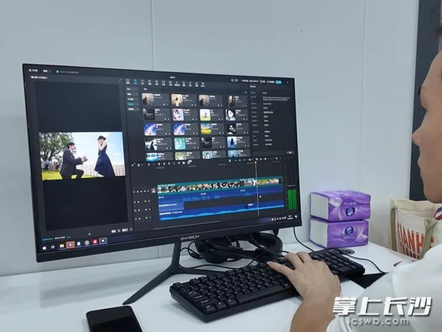 一名工作人员在工位前操作剪辑软件,电脑屏幕展示视频轨道与人物成片预览。
