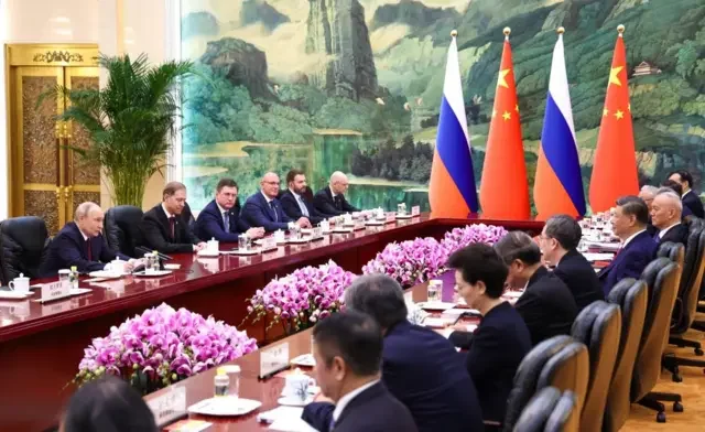 Delegations seated at the negotiating table with Chinese and Russian flags, Great Hall of the People | Source: BBC/Chinese state media