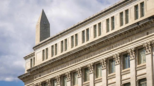 US Department of Agriculture building with Washington Monument behind, blue sky