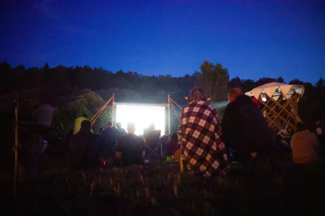 户外夜间露天放映,观众聚集在大银幕前