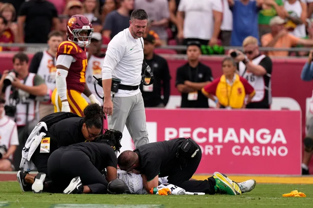 Oregon coach Dan Lanning and medical staff attend to quarterback Dante Moore on the field in Los Angeles