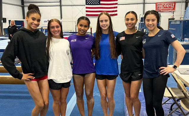 Six senior women gymnasts in USA leotards at team photo at training facility