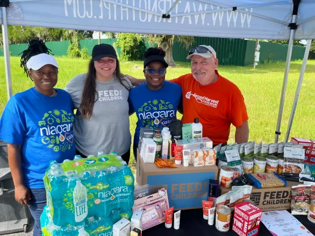 Organizers from Niagara Bottling, Feed the Children and Second Harvest Food Bank of Marion County stand behind a table of food, water and personal-care supplies at the Ocala resource rally.