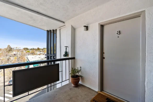 5270 College Ave #8 balcony — terracotta pots, black railings, overlooking Rockridge street scene