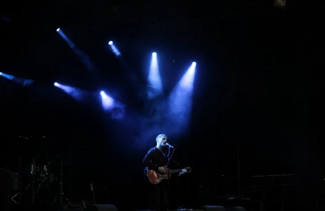 Musician performing solo on stage under dramatic blue spotlights