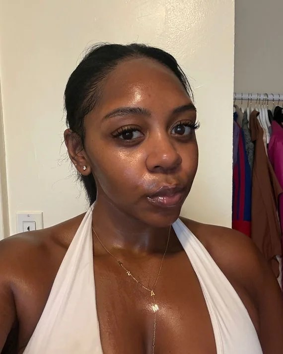 Asia Milia Ware's skin pre-spray — visibly shiny in Miami summer heat, the "before" state Oil Sucker addresses