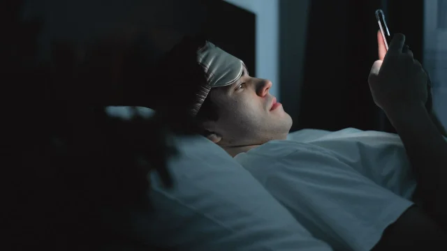 Person in bed looking at a phone at night