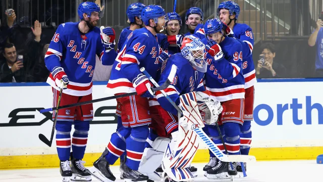 New York Rangers players mobbing goalie Igor Shesterkin on the ice after a goal