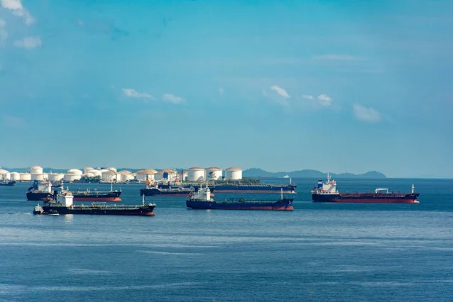 Cargo ships and oil storage tanks at port under blue sky