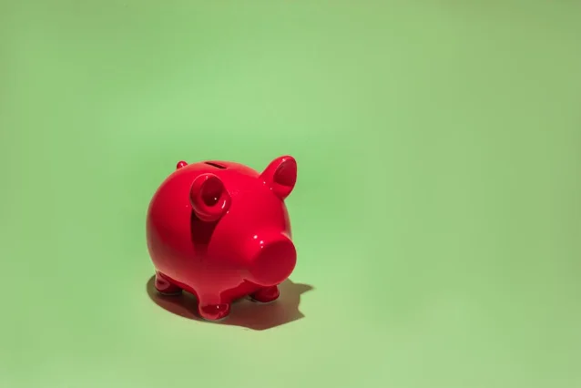 Red piggy bank on a green background representing healthcare savings