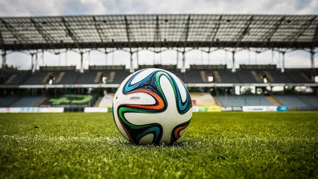 Soccer ball on grass near a stadium