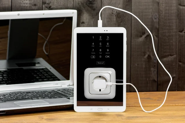 Laptop and tablet charging on a wooden desk
