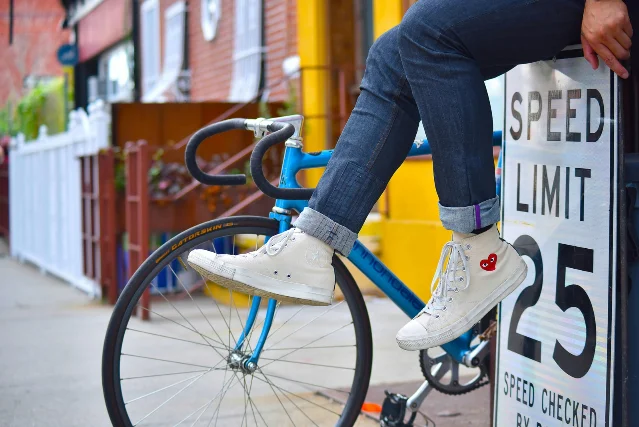 White sneakers next to a bike and speed limit sign in Brooklyn, NY