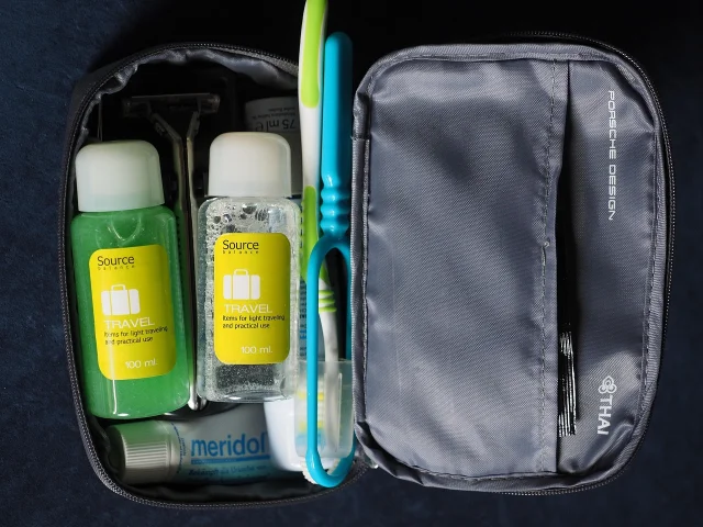 Travel toiletry bag open beside small bottles and toothbrushes